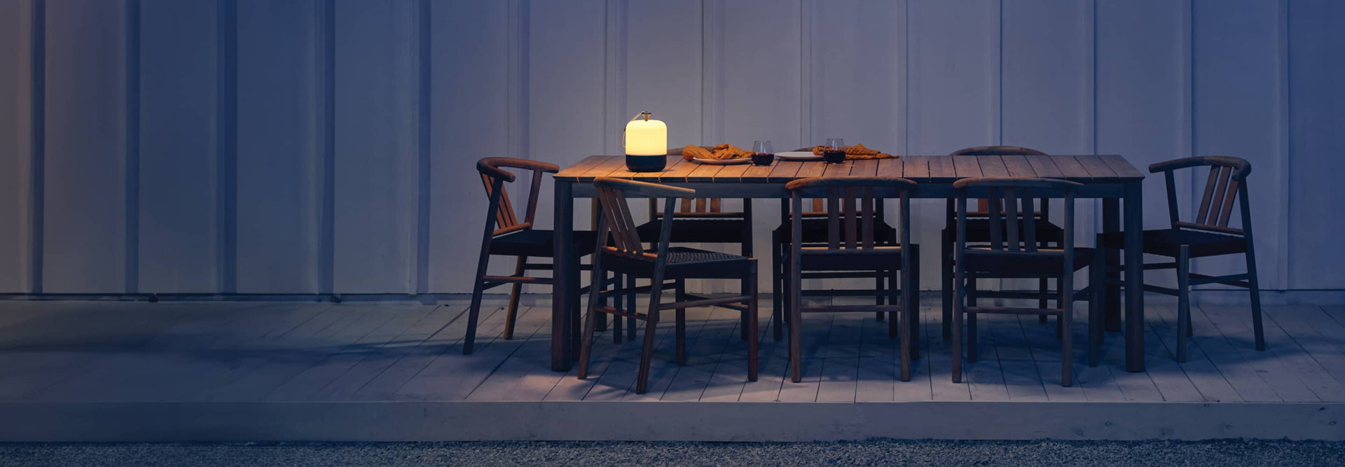 Neighbor teak outdoor dining set at night on a patio deck