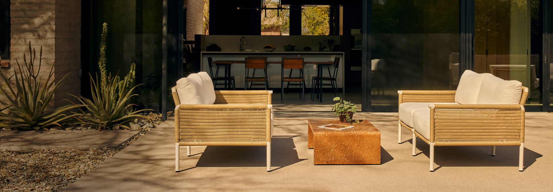 Two wicker loveseats with white cushions on modern back patio