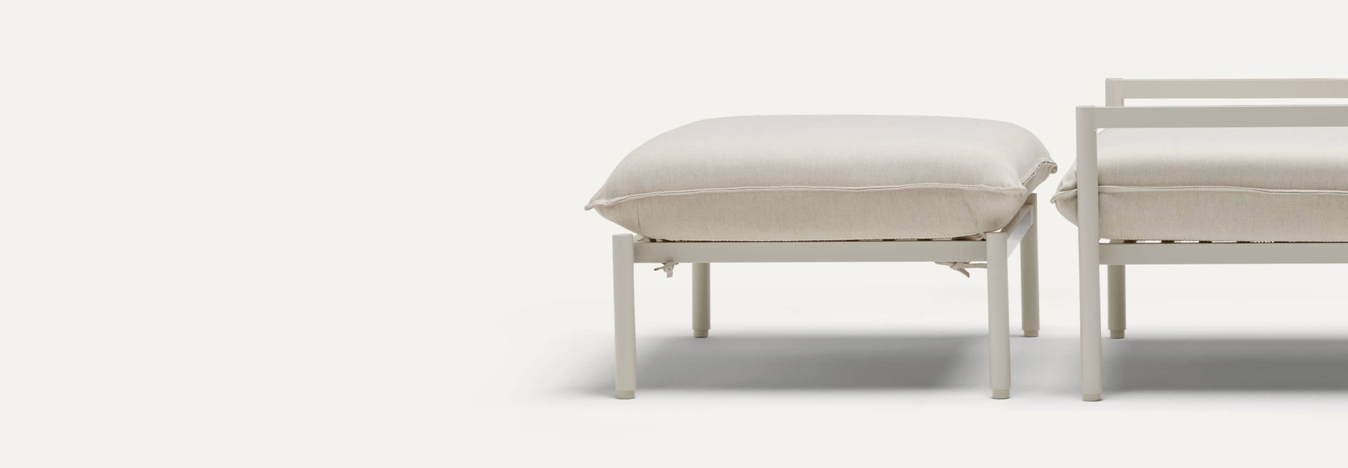 Profile view of an outdoor ottoman, with the frame of a chair cropped off the right edge of the image