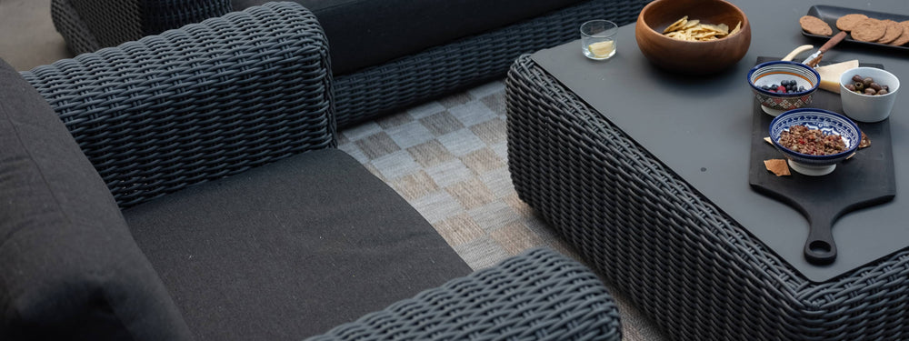 Overhead view of outdoor wicker sofa and coffee table loaded with snacks