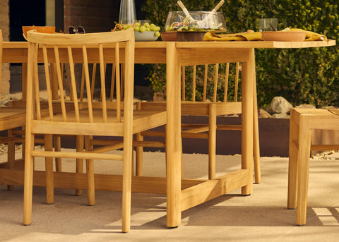 teak outdoor dining table with woman's body in motion in foreground