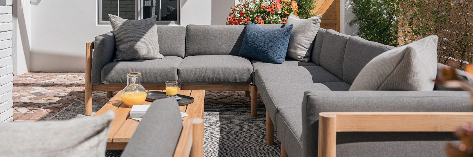 Neighbor outdoor sectional in grey with throw cushions and a teak coffee table