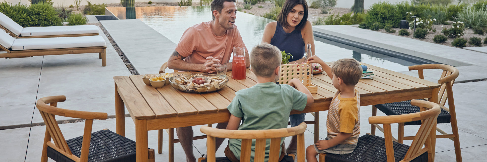 Young family eating outside on a six seater teak dining table and chairs