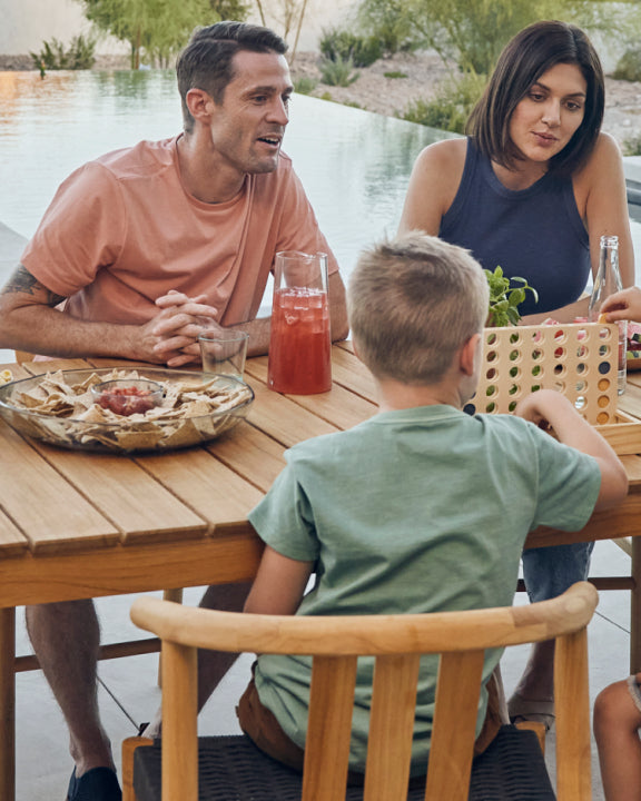 Young family eating outside on a six seater teak dining table and chairs