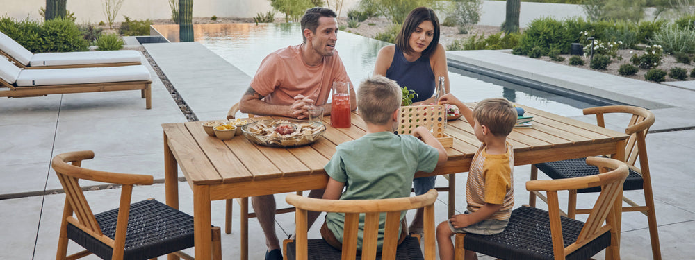 Young family eating outside on a six seater teak dining table and chairs