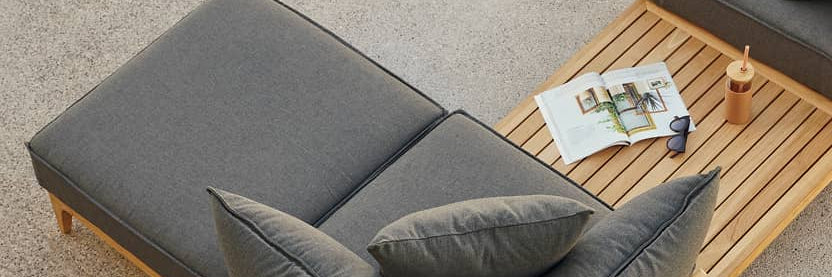 Overhead view of outdoor gray chaise lounge chair with teak frame near pool edge