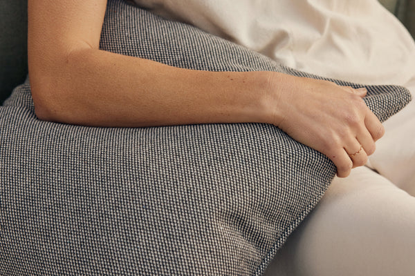 Neighbor black and white outdoor pillow being held by a person sitting on an outdoor sofa