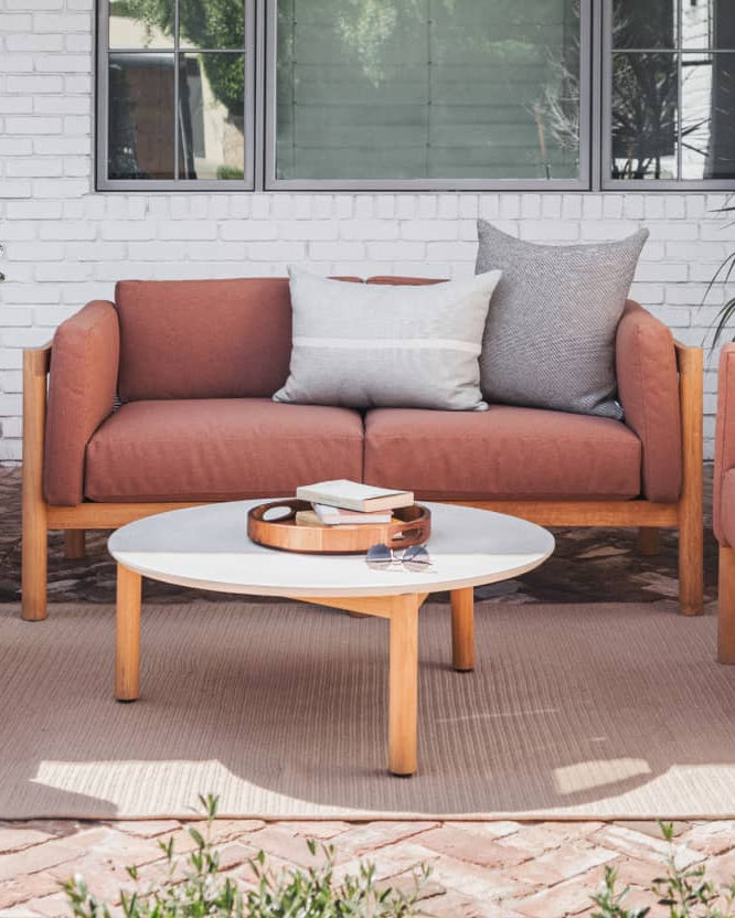 Rust colored upholstered loveseat with plush throw pillows 