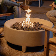 Neighbor round concrete fire pit table in a backyard surrounded by friends sat in teak Adirondack chairs