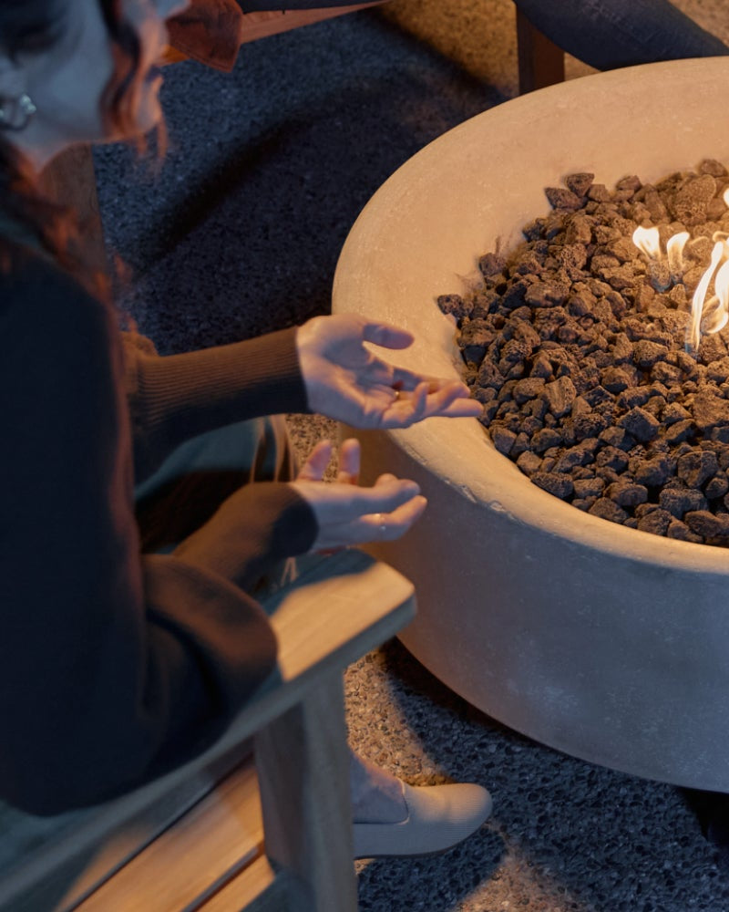 People gathered around a fire pit table with flames in a dimly lit patio