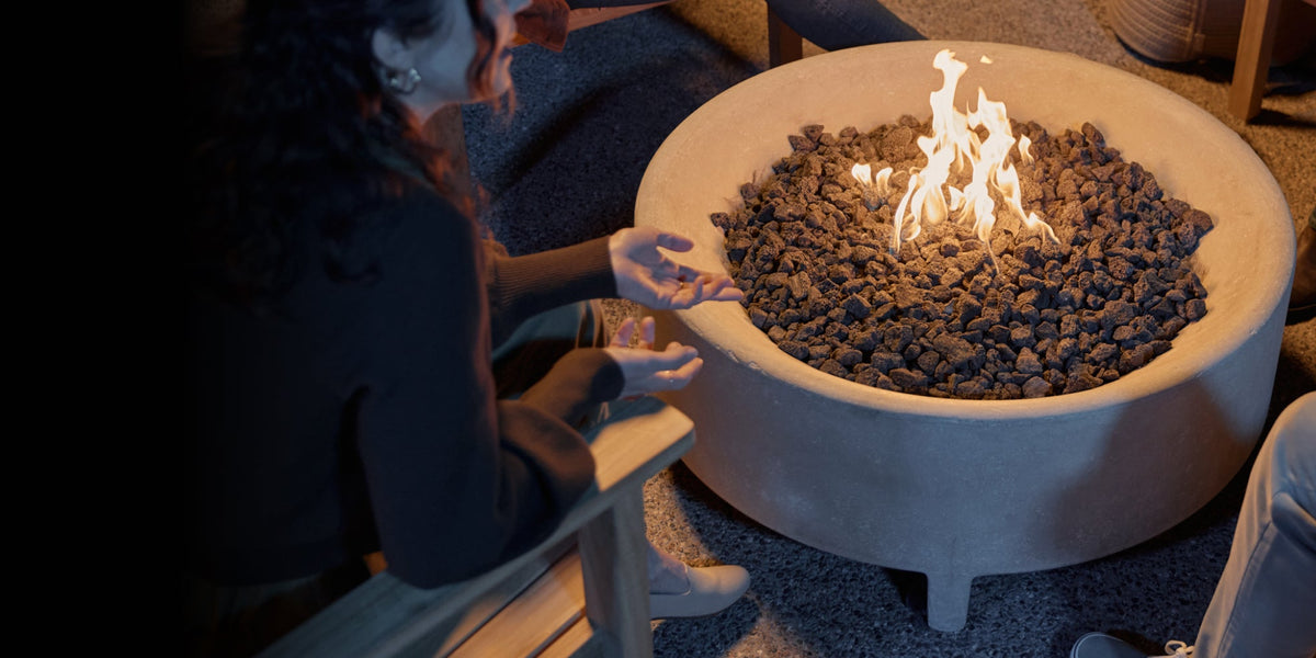 People gathered around a fire pit table with flames in a dimly lit patio