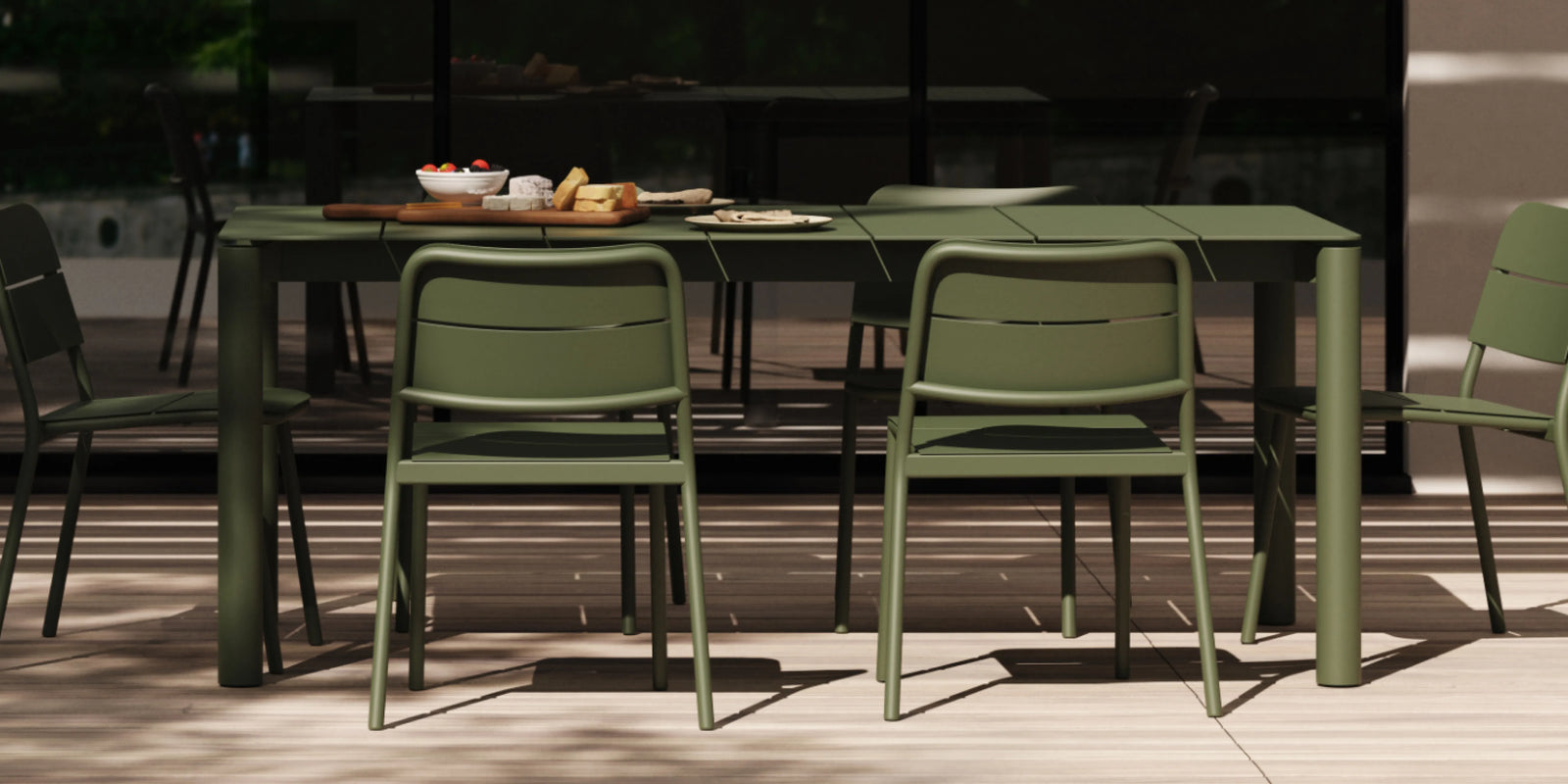 Neighbor Bandwidth Dining Set in Olive on a wood deck with wood-slat wall, afternoon sun