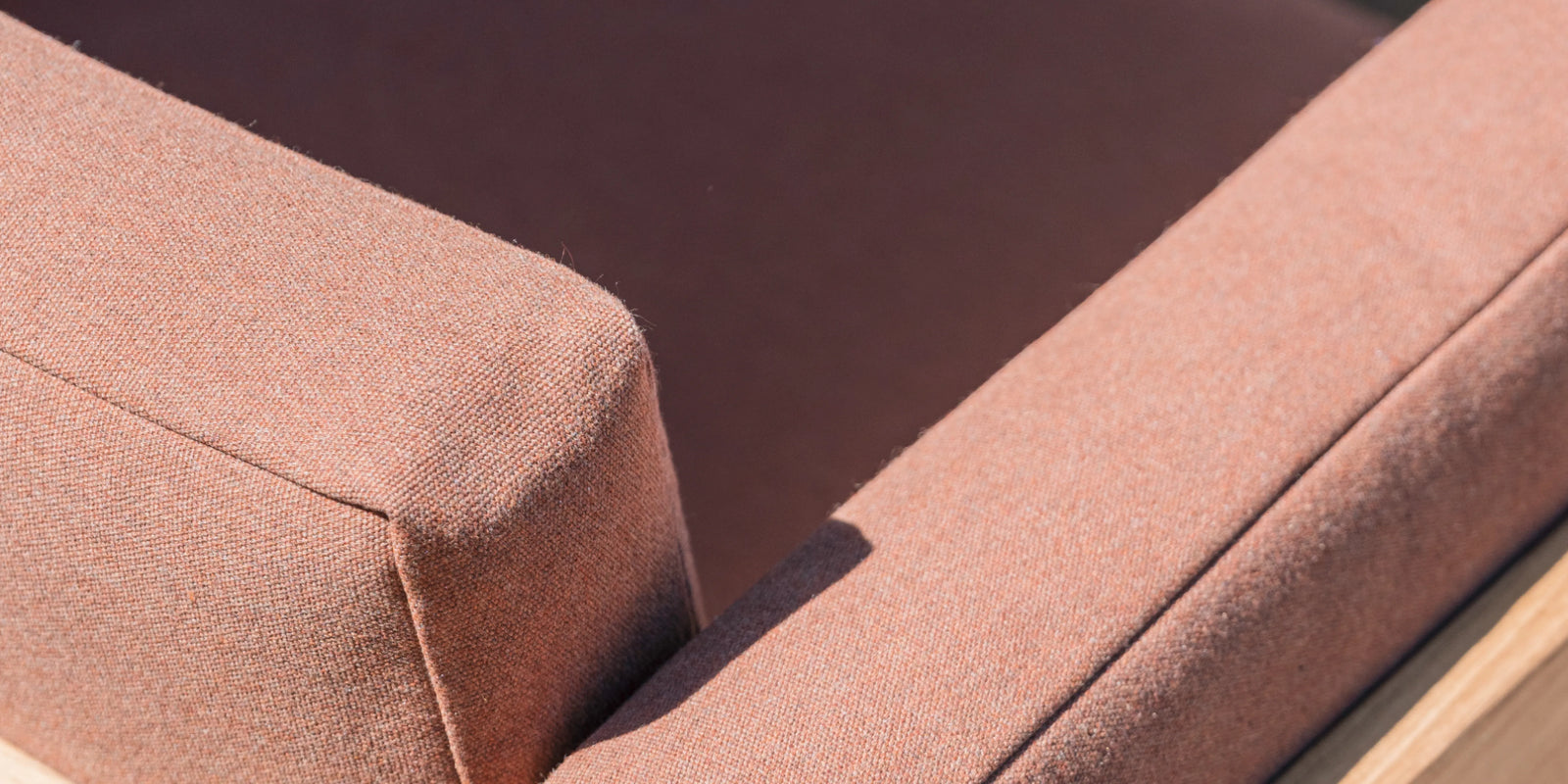 Person seated on Neighbor Haven Chair in charcoal fabric and teak frame on a covered backyard patio