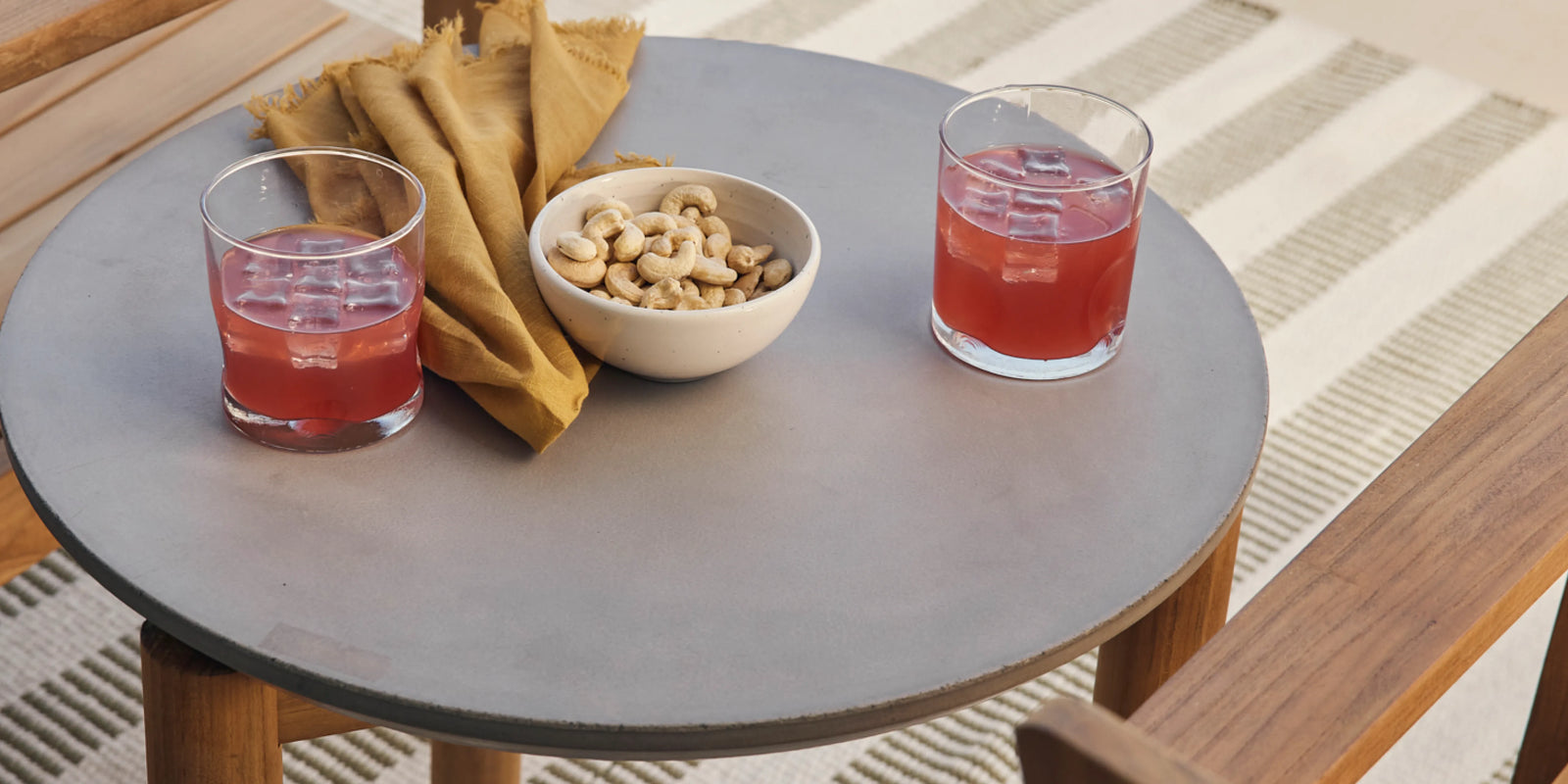 Closeup of Neighbor Haven Side Table concrete top with outdoor chairs and rug in the background