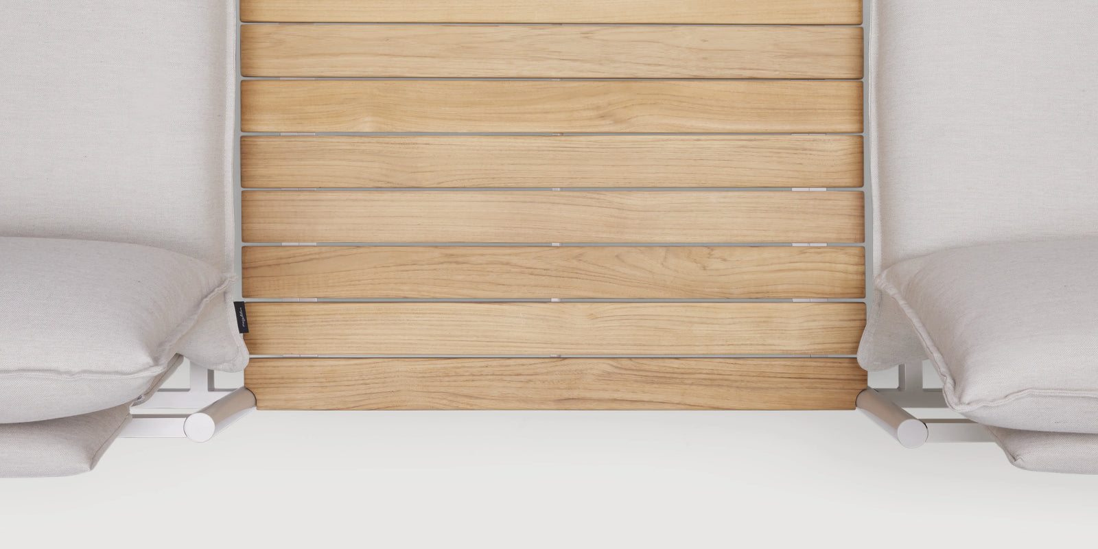 Two women chatting on Neighbor Terra Sofa with In-line Table in cream fabric and teak on a covered wood-slat patio