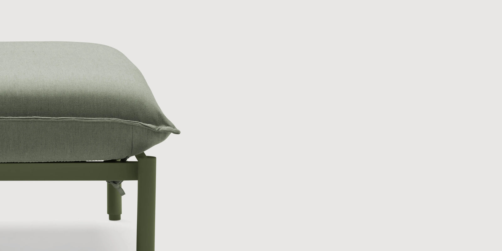 Closeup of Neighbor Terra Ottoman cream fabric top and teak frame corner in outdoor setting