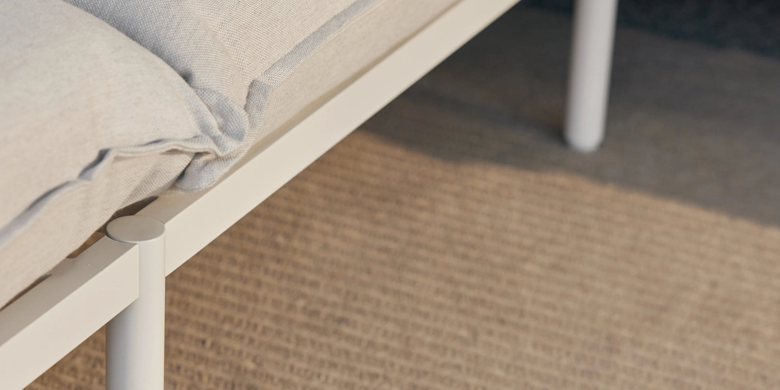 Person's legs on Neighbor Terra Sectional cream cushion with knit blanket, closeup in warm outdoor light