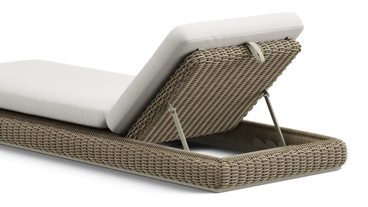 Close-up product photo of a Neighbor Roundabout Sun Lounger in taupe-gray resin wicker, viewed from behind to show the multi-position adjustable backrest mechanism with painted-steel ratchet hinges raising the cream cushion at a relaxed recline angle, isolated on a white background.