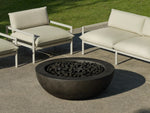 Neighbor Coupe Fire Table in charcoal black with burning stones centered on patio with cream seating nearby.