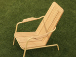 Neighbor Hopper Chair in sand finish, lifestyle shot showing the chair in use on green grass outdoor setting