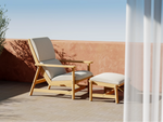 Neighbor Leedo Deck Chair in teak with canvas sling seat and matching ottoman on rooftop patio with clay pot and greenery