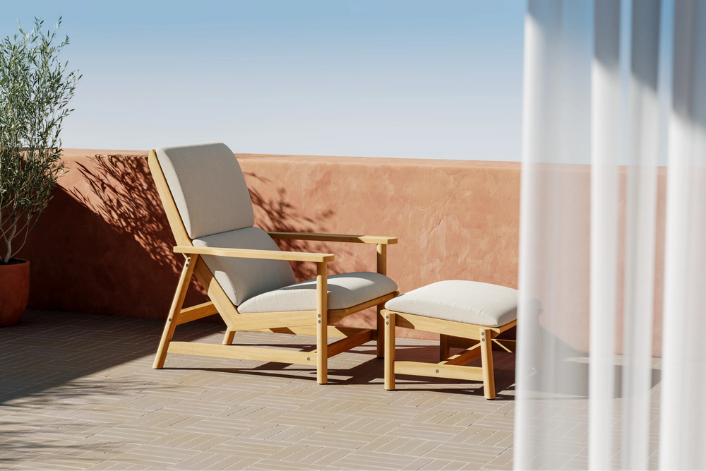 Neighbor Leedo Deck Chair in teak with canvas sling seat and matching ottoman on rooftop patio with clay pot and greenery
