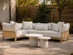Neighbor Ped Coffee Table and Short Side Table in Bone nested before a teak sectional on a sunlit concrete patio