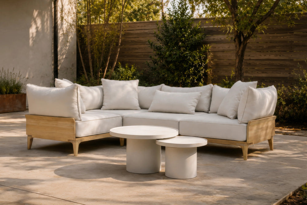 Neighbor Ped Coffee Table and Short Side Table in Bone nested before a teak sectional on a sunlit concrete patio