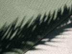 Neighbor Braid Rug in Basil colorway detail, striped diagonal pattern with plant shadows cast across green textured surface
