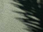 Neighbor Braid Rug in Basil, close-up showing woven texture with diagonal leaf shadows on soft sage-green fabric
