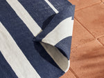 Neighbor Mesa Rug in Indigo with navy and cream striped geometric pattern, corner folded showing layered fabric