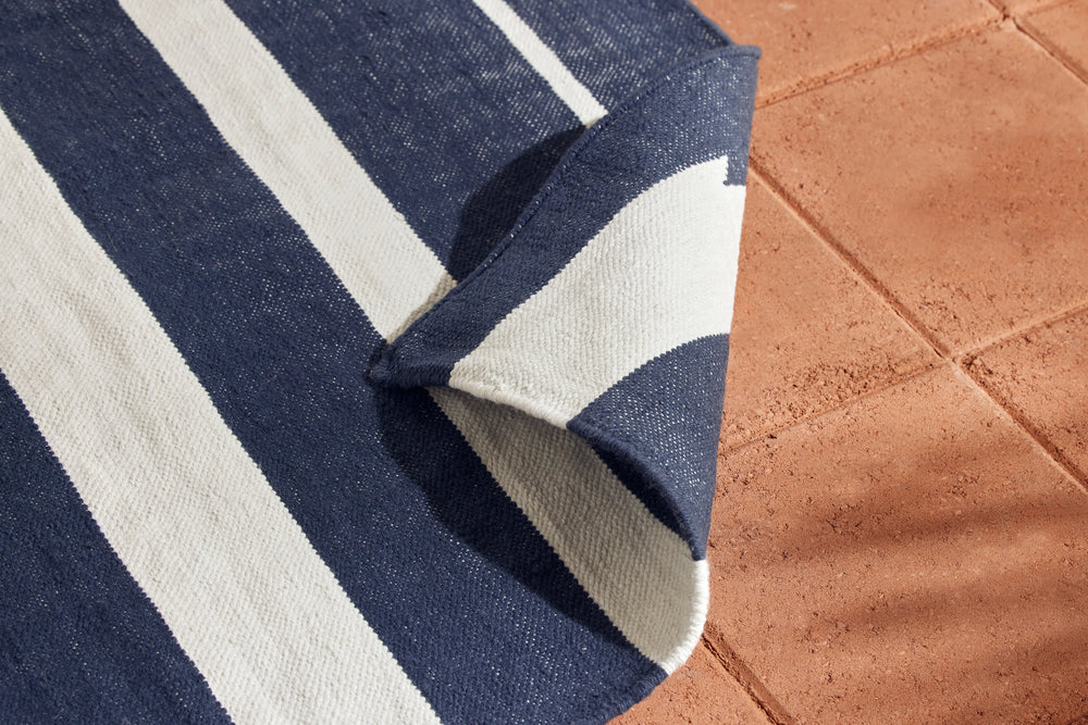 Neighbor Mesa Rug in Indigo with navy and cream striped geometric pattern, corner folded showing layered fabric