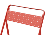 Neighbor Take Two Bistro Chair, an all-metal folding chair with perforated steel seat and backrest in coral red, close-up of the perforated steel seat.