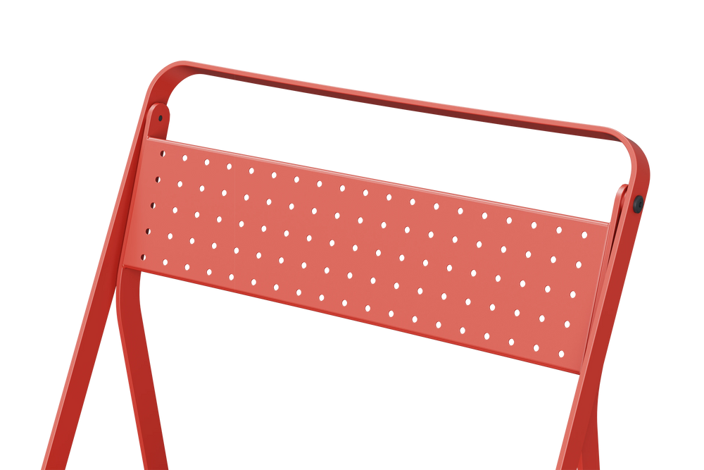 Neighbor Take Two Bistro Chair, an all-metal folding chair with perforated steel seat and backrest in coral red, close-up of the perforated steel seat.