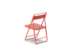 Neighbor Take Two Bistro Chair, an all-metal folding chair with perforated steel seat and backrest in coral red, rear three-quarter angle view.