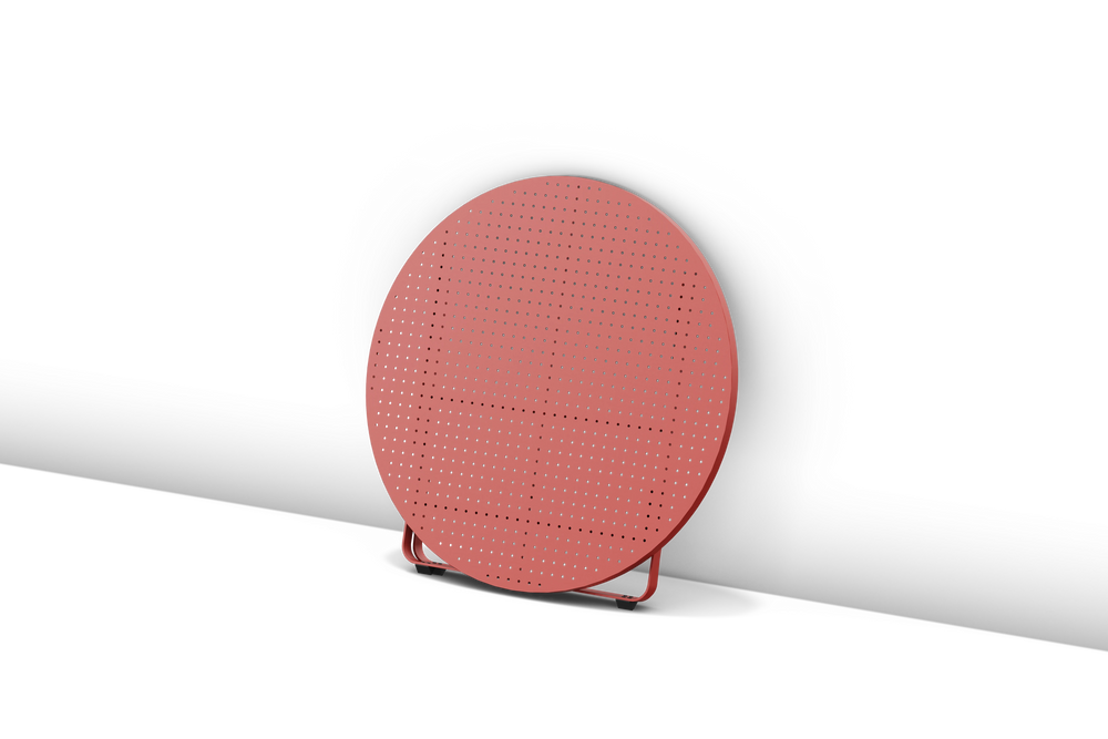 Neighbor Take Two Coffee Table, a round folding outdoor coffee table with a perforated steel top in coral red, shown fully folded for storage.