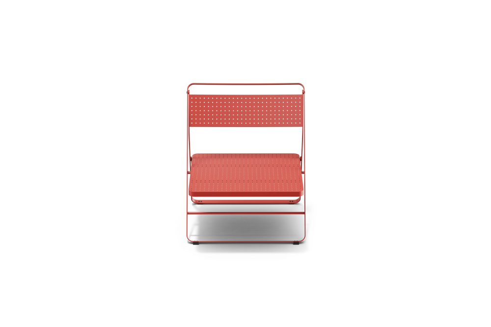 Neighbor Take Two Lounge Chair, a low-slung folding chair with perforated steel seat and backrest in coral red, front view.