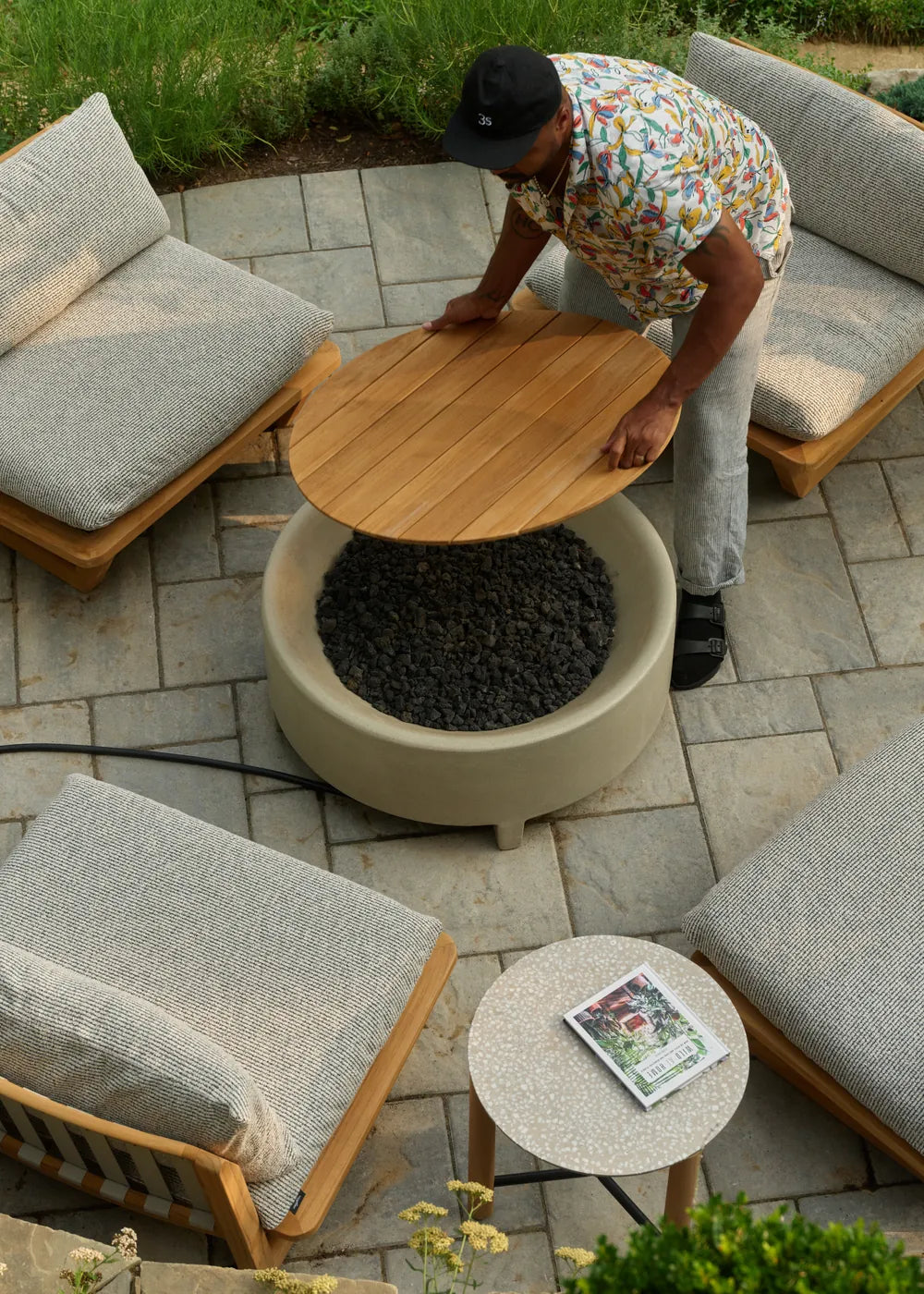 Overhead view of Hilton Carter's stone patio with a Rook fire table, Dweller lounge chairs and a Haven round side table