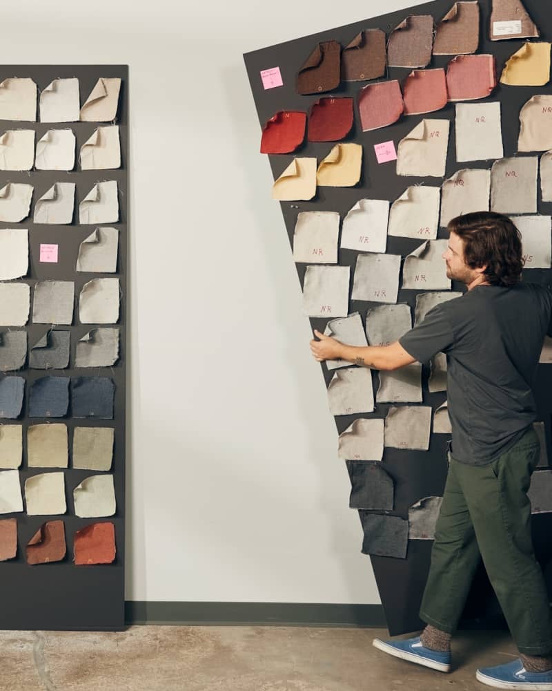 Designer arranging fabric and material swatches on a large display board in a studio