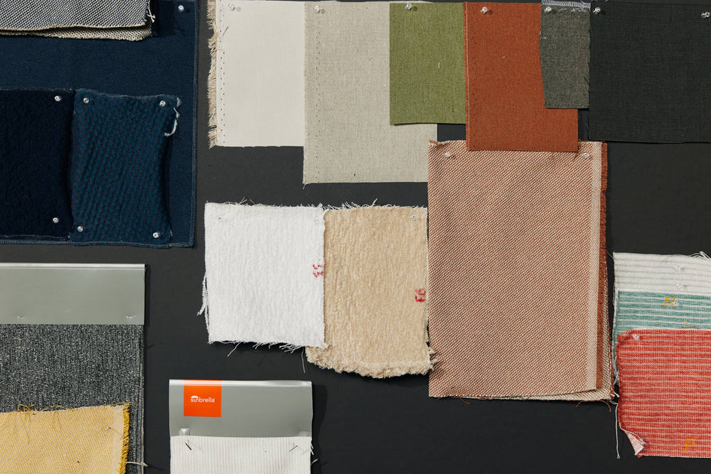 Squares of multi-colored textile swatch samples pinned to black wall.