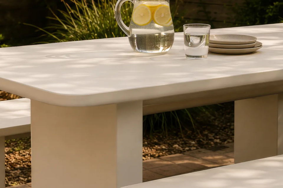 Angled view of the Massif Dining Set, an ivory concrete composite table with rounded corners and two integrated benches.