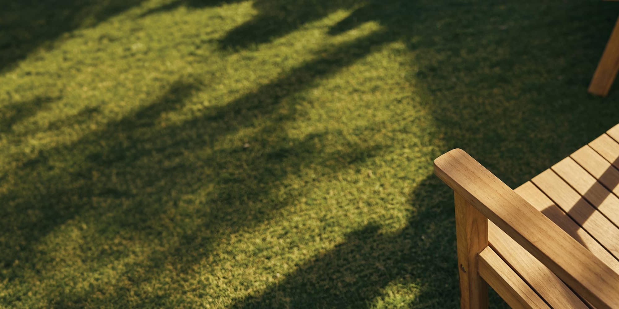 Cropped overhead teak Adirondack chair on green turf.