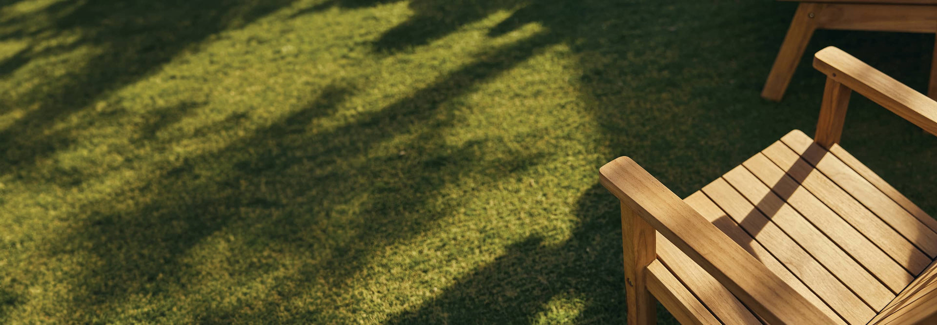 Cropped overhead teak Adirondack chair on green turf.