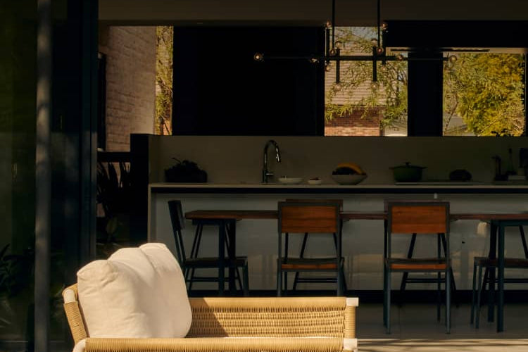 Two wicker loveseats with white cushions on modern back patio