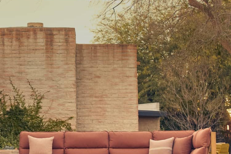 Neighbor Teak sectional with rust-colored cushions with coffee table and chairs on pool deck against a modern home