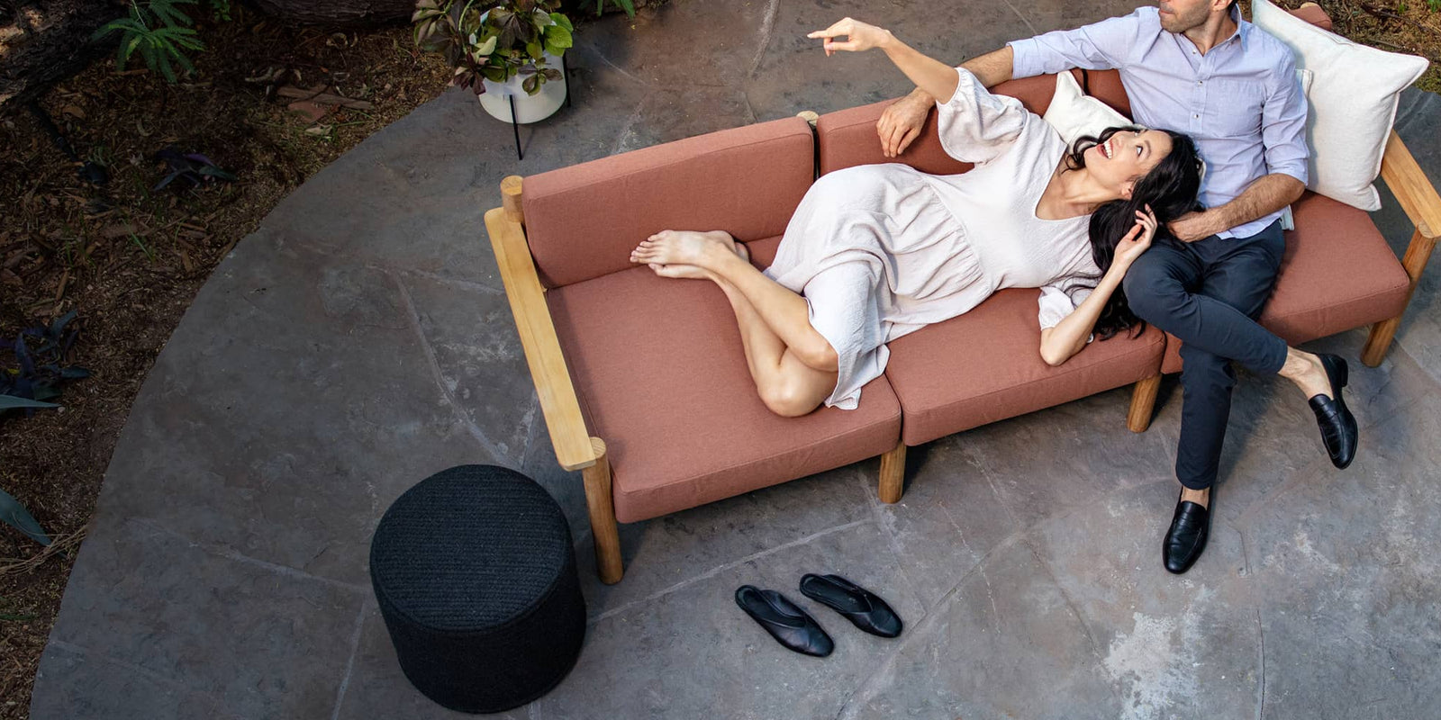 Couple comfortably laying on rust-colored outdoor sofa together