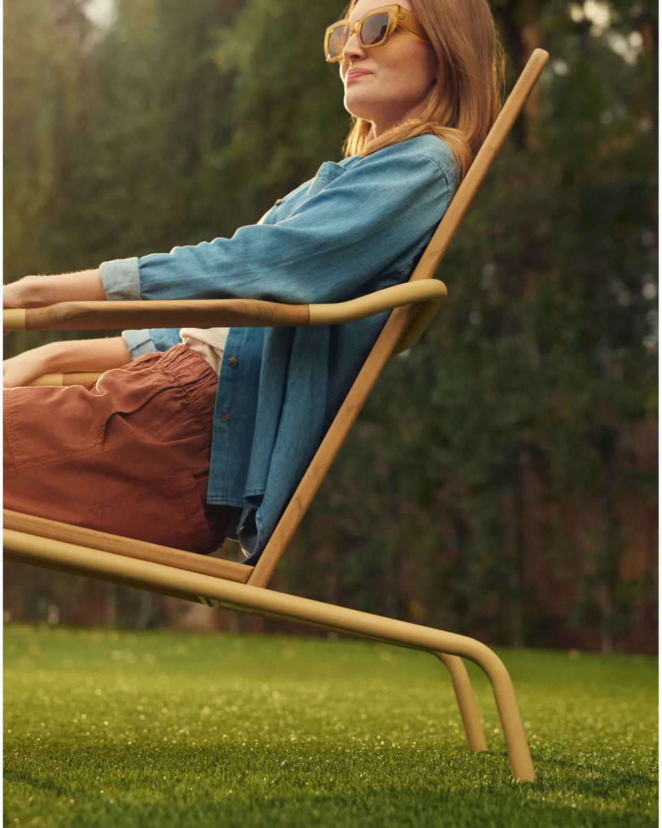 Woman relaxing on a Hopper Chair with green grass in the background