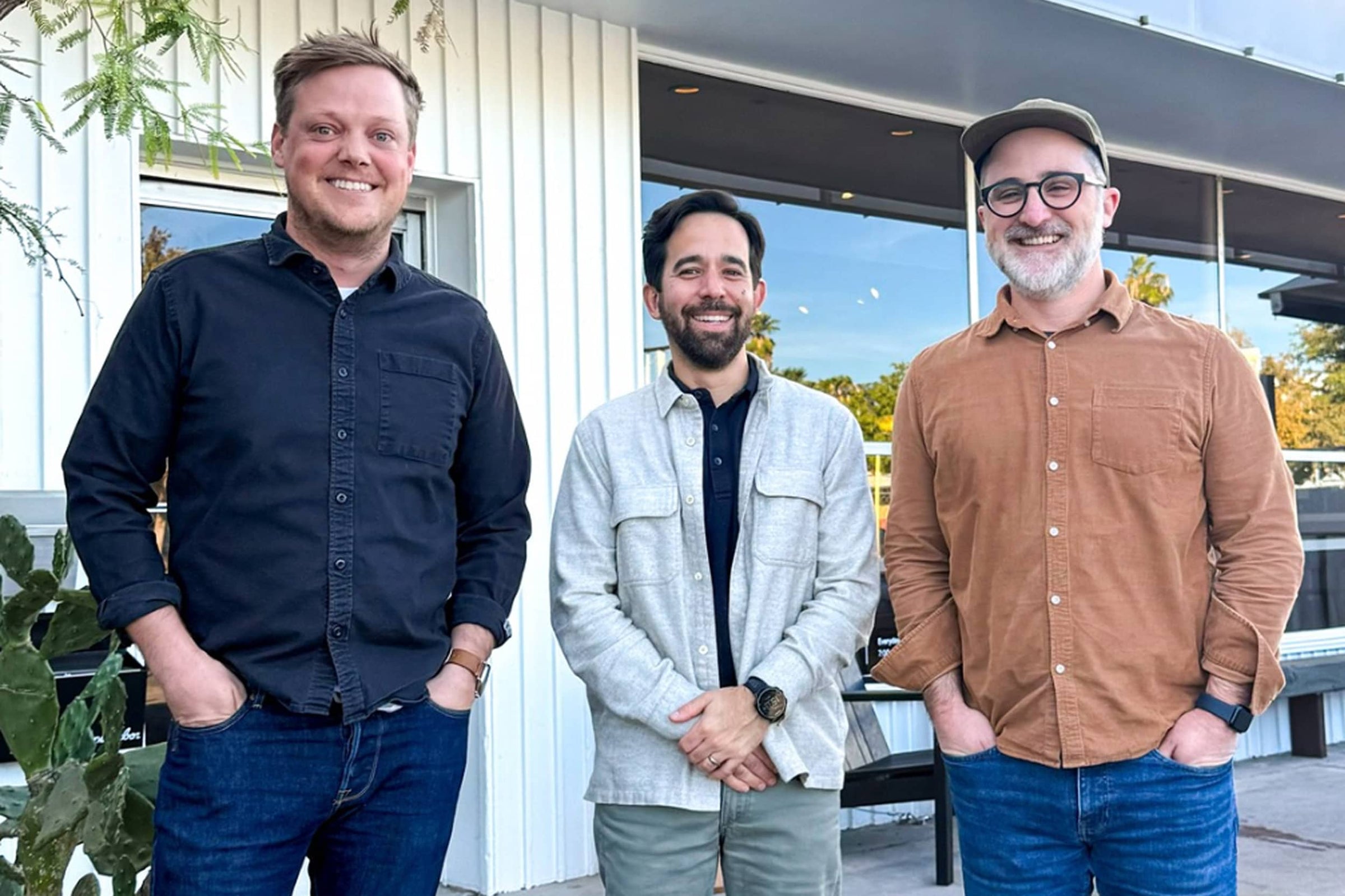 Three  co-founders standing outdoors in front of a white building