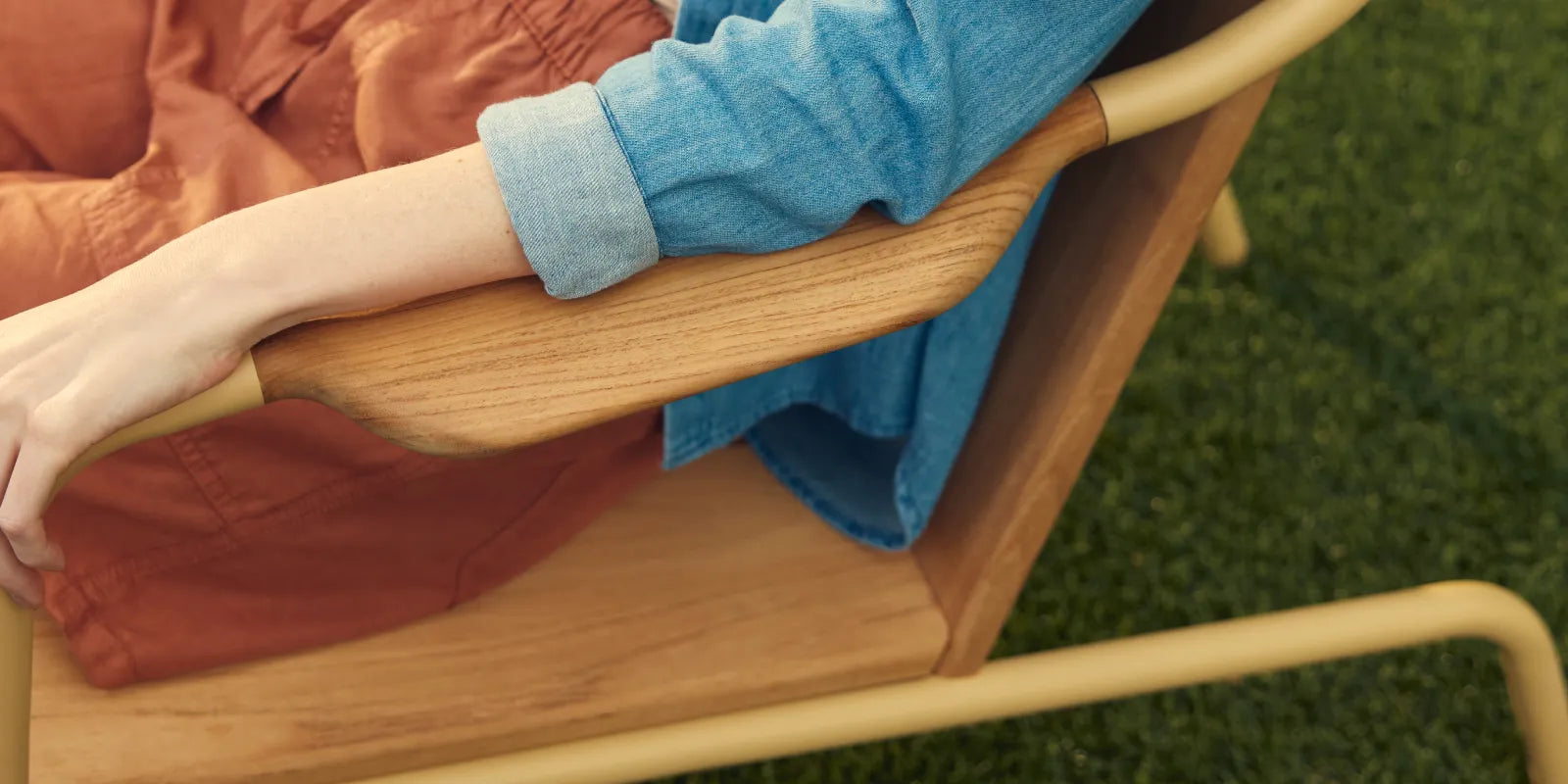 Person relaxing in Hopper Chair on grass with feet up on Ottoman, demonstrating lounge functionality
