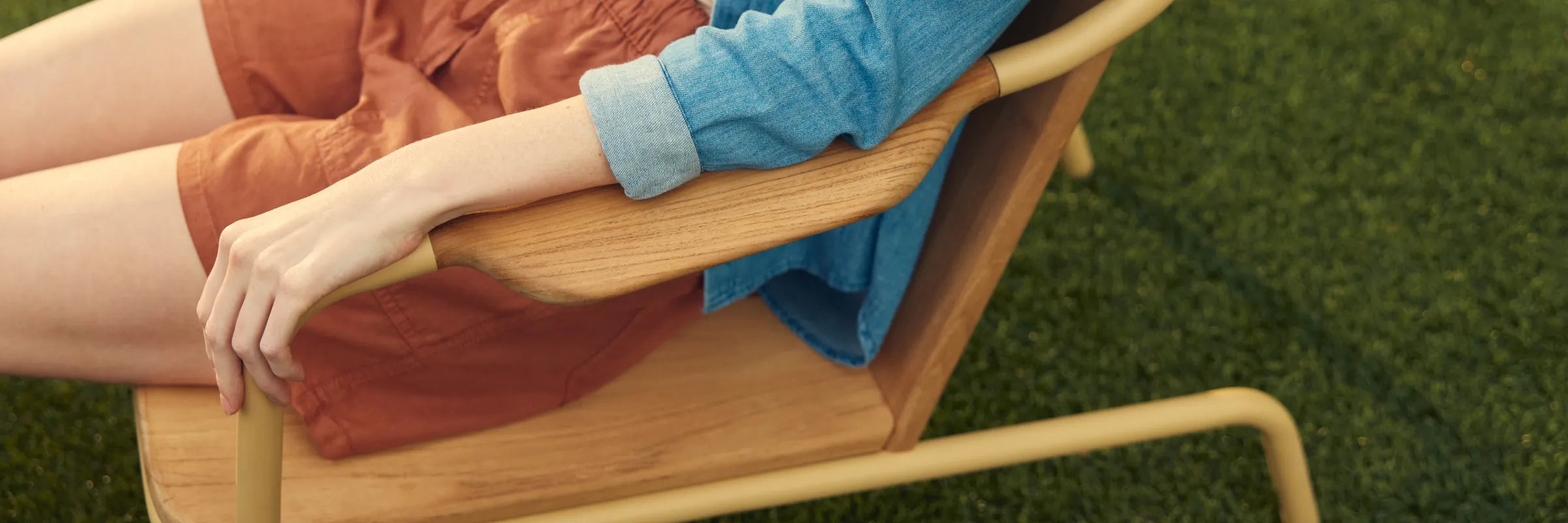 Person relaxing in Hopper Chair on grass with feet up on Ottoman, demonstrating lounge functionality